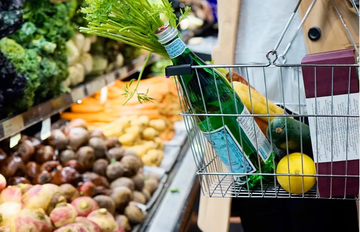 Shot of a shopper's basket with various items, in a supermarket, in front of produce, 